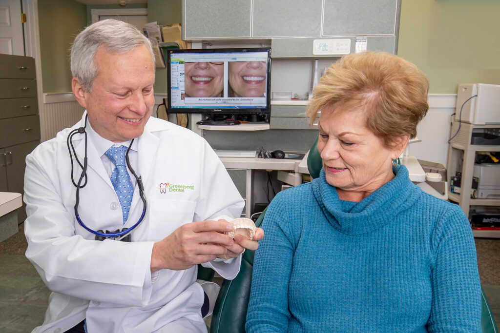 Dr. Randy Greenberg shows a patient a 3D teeth model