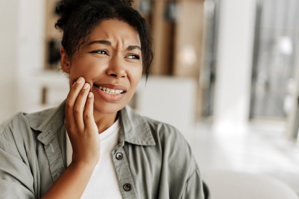 Young woman suffering from strong toothache at home